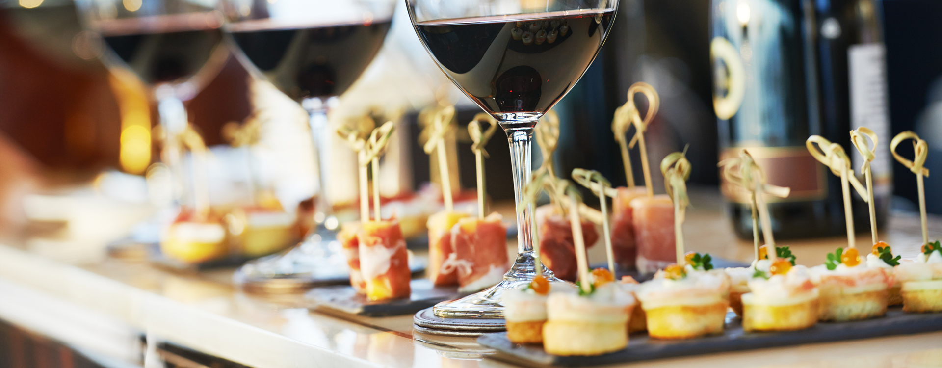 A glass of red wine and a fancy dessert on a white tablecloth, represent fine dining.